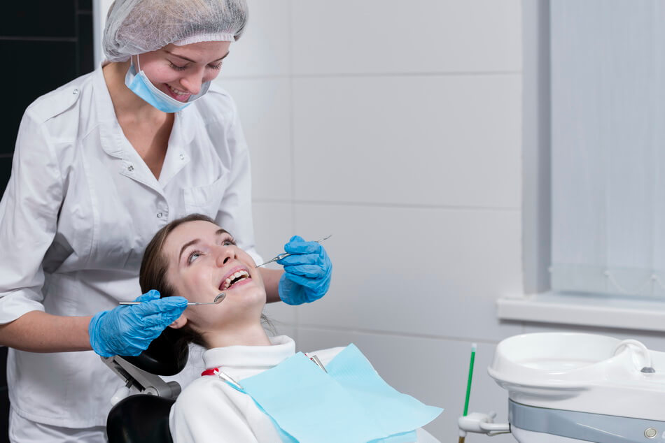 female-dentist-performing-dental-check-patient تنظيف الاسنان - Teeth cleaning