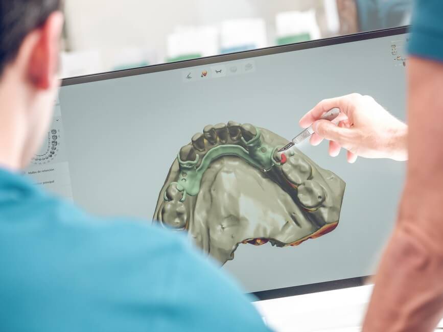 dentist-pointing-at-monitor-with-jaw-model زراعة الأسنان الرقمية - Digital Dental Implants